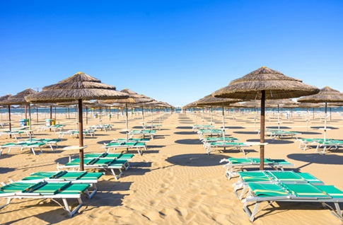 Türkise Liegestühle und braune Sonnenschirme am Strand. 