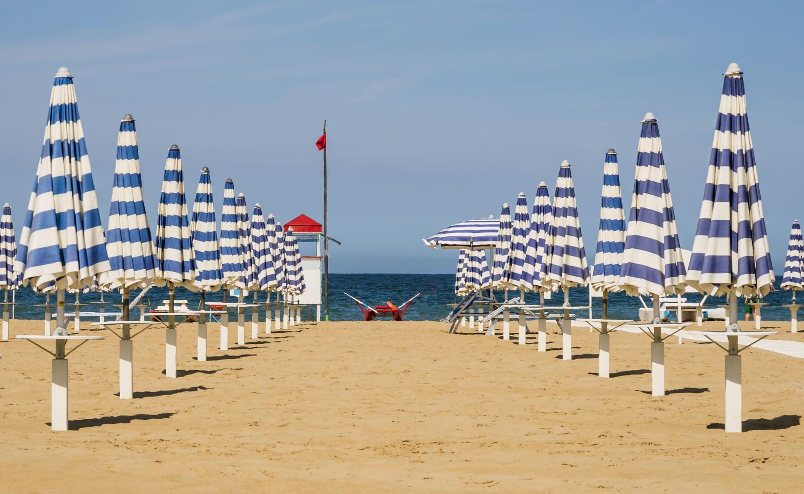 Blau-weiß gestreifte Sonnenschirme am Strand. 